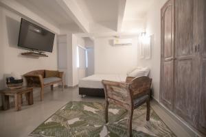 um quarto com uma cama, uma televisão e uma cadeira em Gastelbondo Centro Histórico Plaza Santo Domingo em Cartagena das Índias