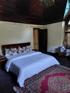 ein Schlafzimmer mit einem großen Bett mit weißen Laken und Kissen in der Unterkunft Dalhousie Heritage Cottage in Nainital
