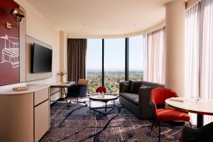 a living room with a couch and a tv at Mercure Melbourne Doncaster in Doncaster