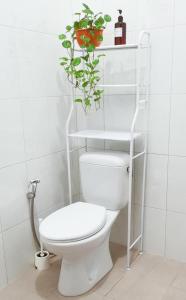 a bathroom with a white toilet with a plant on the shelf at Snooze Ijen in Banyuwangi