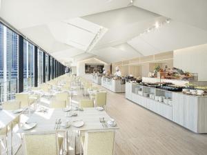 a restaurant with white tables and chairs and windows at Hotel Royal Classic Osaka in Osaka