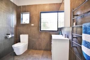 a bathroom with a toilet and a sink and a window at Bluetongue at Culburra I Pet Friendly 4 Mins to Beach in Culburra Beach +14 photos