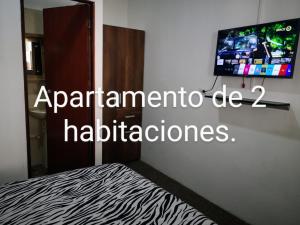 a bedroom with a bed and a tv on a wall at Cómodos y acogedores Apartaestudios - Manizales in Manizales