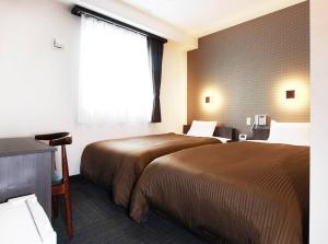 大阪市にあるホテルトレンド西心斎橋のベッド2台と窓が備わるホテルルームです。