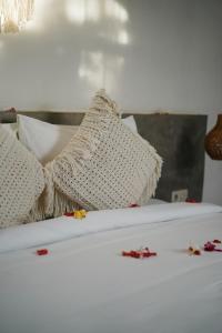 Suku Lifestyle Hotel في سيلونغ بيلاناك: سرير ابيض عليه مخدات بيضاء وزهور