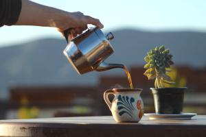 eine Person, die Kaffee in eine Kaffeetasse gießt in der Unterkunft Entrevalle Hotel Boutique in Valle de Guadalupe