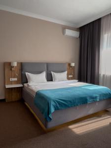 a bedroom with a large bed with a blue blanket at Keremet Hotel in Almaty