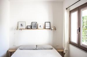 una camera bianca con un letto e una finestra di Residenze Branca I SeaView a Orosei
