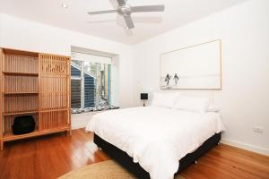 a white bedroom with a bed and a ceiling fan at Ayana - Pet Friendly - Directly Opposite Beach - Fireplace in Currarong