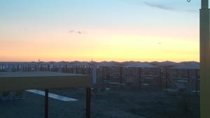 - une vue sur une plage dotée de chaises et de parasols au coucher du soleil dans l'établissement Hotel Laurin, à Lido di Camaiore