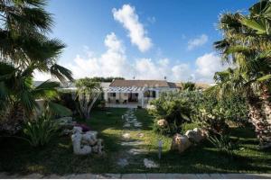 a house with a yard with palm trees and plants at Villa con piscina in San Vito lo Capo