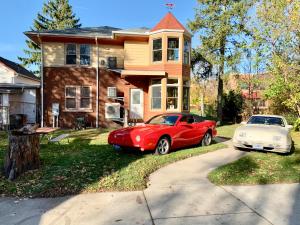 a red car and a white car parked in front of a house at The Avanti Houses in South Bend