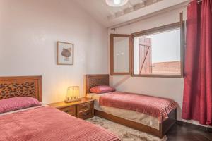 1 dormitorio con 2 camas y ventana en Chalet Asmoun 2 en Imouzzer Kandar