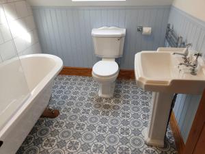 a bathroom with a toilet and a sink and a tub at Pebble Cottage, Cromer in Cromer