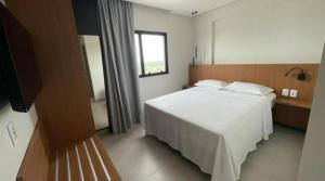 ein Schlafzimmer mit einem weißen Bett und einem Fernseher in der Unterkunft SALINAS PREMIUM RESORT in Salinópolis