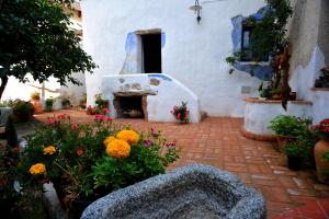 un jardín con flores frente a un edificio blanco en B&B Corte San Lussorio, en Oliena