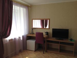 a room with a desk and a television and a window at Grad Hotel in Cherepovets
