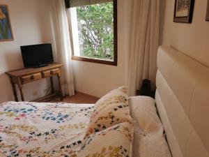 1 dormitorio con 1 cama, TV y ventana en Apartamento VOLVERÁS, en Sanxenxo
