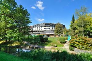 un edificio en un parque junto a un río en Hotel Smarjeta - Terme Krka, en Smarjeske Toplice