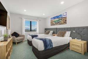 a hotel room with two beds and a chair at Exciting Queenstown in Queenstown