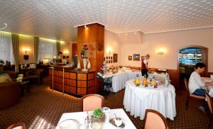 a restaurant with white tables and people sitting around it at Hotel Binz in Bernkastel-Kues