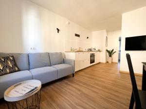 Il comprend un salon avec un canapé bleu et une cuisine. dans l'établissement Ferienwohnung im Zentrum von Kaltern, à Caldaro