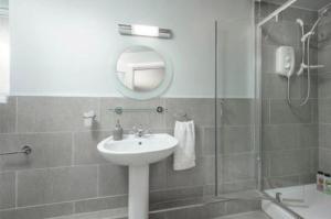 y baño con lavabo, espejo y ducha. en Newminster Cottage en Morpeth