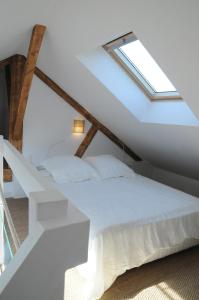 une chambre avec un lit blanc avec une lucarne dans l'établissement L'équipage - Hyper centre, charme et calme à deux pas de la mer, à Cabourg