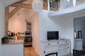 un salon avec une télévision et une cuisine dans l'établissement L'équipage - Hyper centre, charme et calme à deux pas de la mer, à Cabourg 11 autres photos