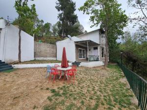 una mesa con sillas y una sombrilla roja en un patio en 2BHK ALPINE VILLA, en Lansdowne