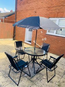 a table with four chairs and an umbrella at Cheerful home near City Centre,Station& RaceCourse in Doncaster