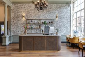 a restaurant with a reception desk and a chandelier at Hotel Royal Bridges in Delft