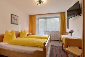 a bedroom with two beds with yellow sheets and a television at Haus Traudl in Mayrhofen