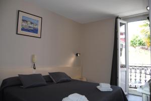 a bedroom with a black bed and a balcony at Hôtel Acropolis in Lourdes