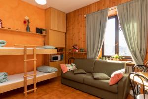 un soggiorno con divano e letto a castello di Comfort studio centro Aprica vicino piste da sci ad Aprica