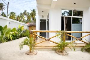 a white house with a wooden fence and palm trees at Hi Zanzibar in Paje