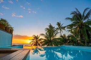 una piscina con palmeras y el océano al atardecer en Signature Boracay formerly La Banca House en Boracay