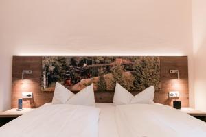 Zwei weiße Betten in einem Zimmer mit einem Bild an der Wand in der Unterkunft Familien Apartmenthotel Panoramic in Bad Lauterberg + 47 Fotos