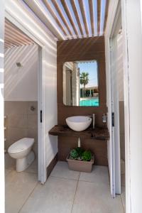 a bathroom with a sink and a toilet and a mirror at Aqua Venere Pool & Suites in Marsala