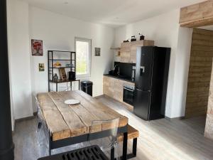 eine Küche mit einem Holztisch und einem schwarzen Kühlschrank in der Unterkunft magnifique appartement cosy et familial in Valdeblore