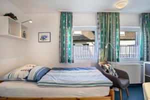 a bedroom with a bed and a chair and a window at Nordhaus Ferienwohnung 6 in Duhnen