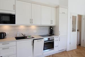 una cocina blanca con armarios blancos y fregadero en Zu Besuch im Palast - Perfekte Lage, en Dresden