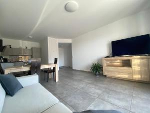 uma sala de estar com um sofá e uma televisão de ecrã plano em Appartement T2 de standing avec parking à 250 mètres de la plage, route des Sanguinaires, Ajaccio em Ajaccio