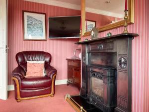 a living room with a leather chair and a fireplace at Duinin House B&B in Dingle