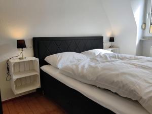 Cette chambre comprend un grand lit avec des draps blancs et 2 lampes. dans l'établissement Schickes Appartement in Residenznähe, à Wurtzbourg