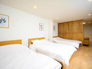2 Betten in einem Zimmer mit weißer Bettwäsche in der Unterkunft K's Hotel in Takamatsu