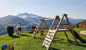 a child playing on a swing set with mountains in the background at Bichlgut in Bischofshofen