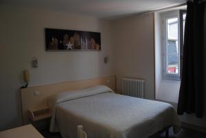 a small bedroom with a bed and a window at Hôtel Acropolis in Lourdes