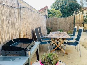 une arrière-cour avec un grill, une table et des chaises dans l'établissement Maisonnette du coteau ouest - Jardin et terrasse - Epernay, à Épernay