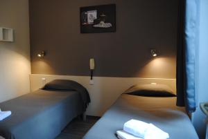 Habitación con 2 camas y teléfono en la pared. en Hôtel Acropolis en Lourdes